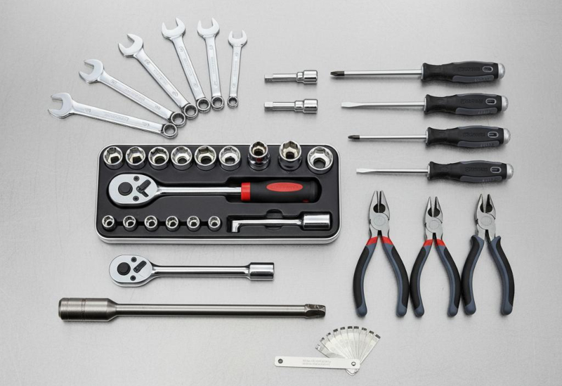Professionelles Kfz-Handwerkzeug von oben: Schraubenschlüssel, Steckschlüsselsatz, Ratsche, Zangen und Drehmomentschlüssel auf Metallwerkbank