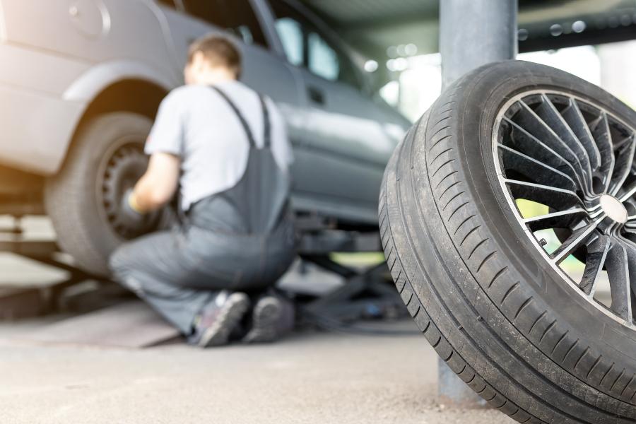 Mechaniker wechselt Reifen in der Werkstatt - Service Reifeneinlagerung und Räderwechsel