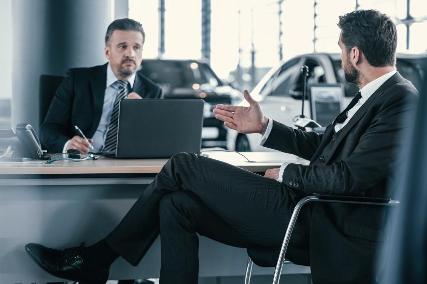 2 Männer in einem Autohaus unterhalten sich - Arbeitsplanung im Fahrzeughandel