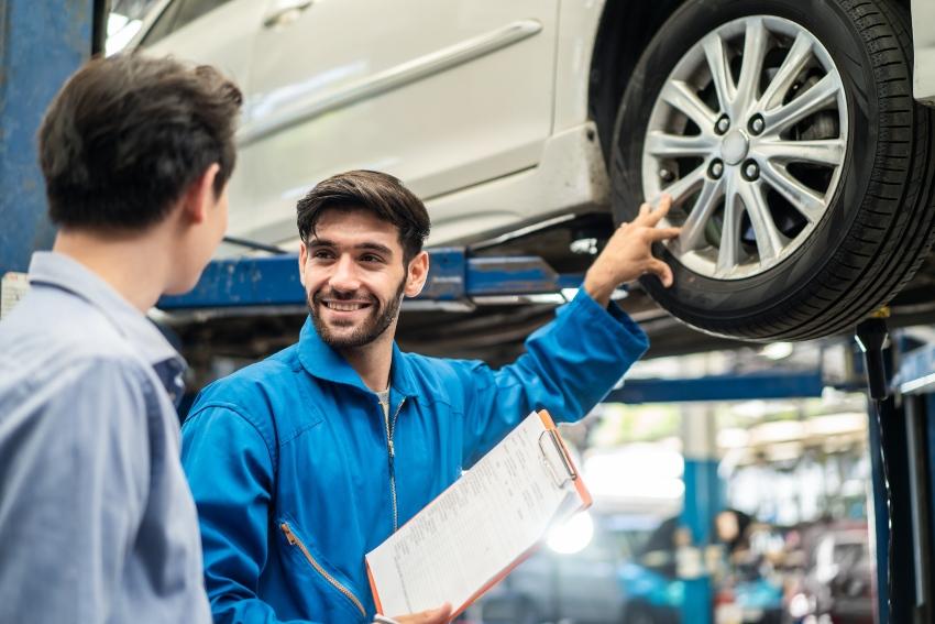 Automechaniker erklärt Kunden die Reparatur am Reifen
