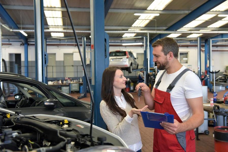 Ein Mechaniker übergibt nach erfolgreicher Reparatur der Kundin ihren Fahrzeugschlüssel Schlüsselmanagement