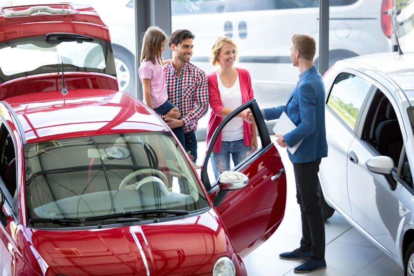 Junge Familie kauft Auto im Autohaus - Neueröffnung im Autohaus mit Angeboten an Familien