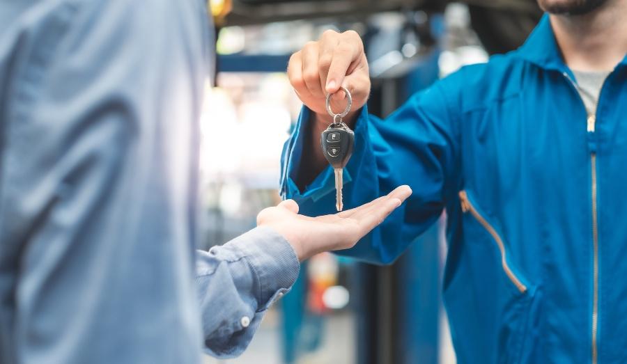 Automechaniker händigt Schlüssel aus - Schlüsselverwaltung dank kleiner Helfer