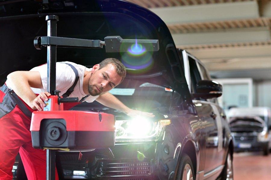 Ein Mechaniker führt einen Scheinwerfertest an einem PKW in der Werkstatt durch 