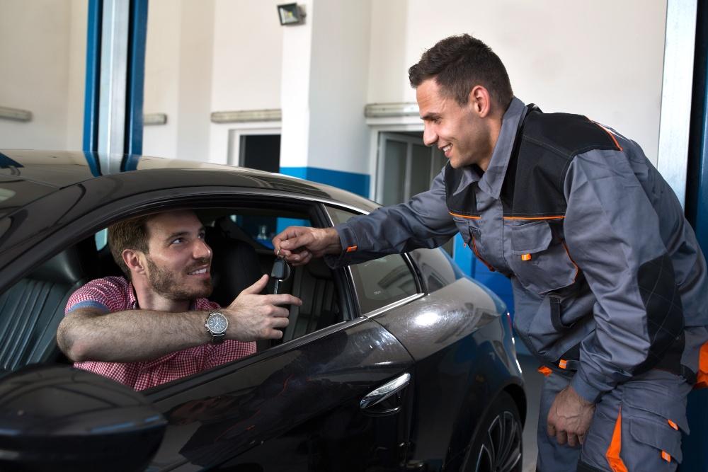 Mechaniker drückt Kunden den Autoschlüssel in die Hand