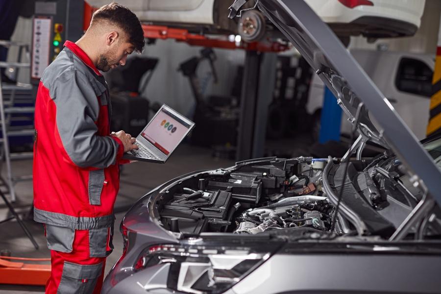 Mechaniker prüft Auto mittels Laptop die Elektronik 