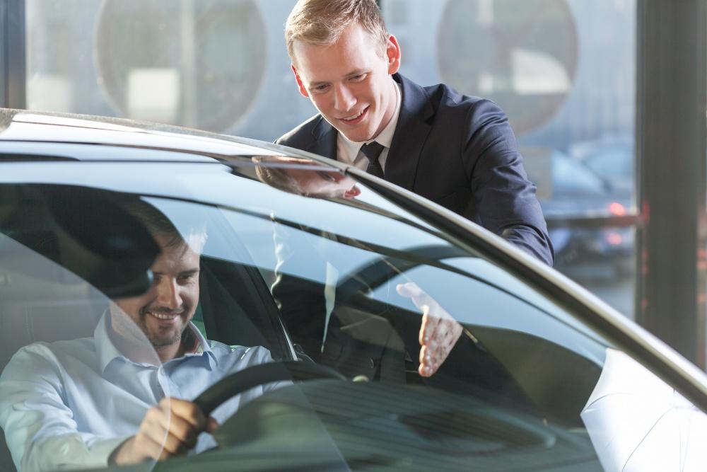 Junger Mann im Autohaus in einem Auto