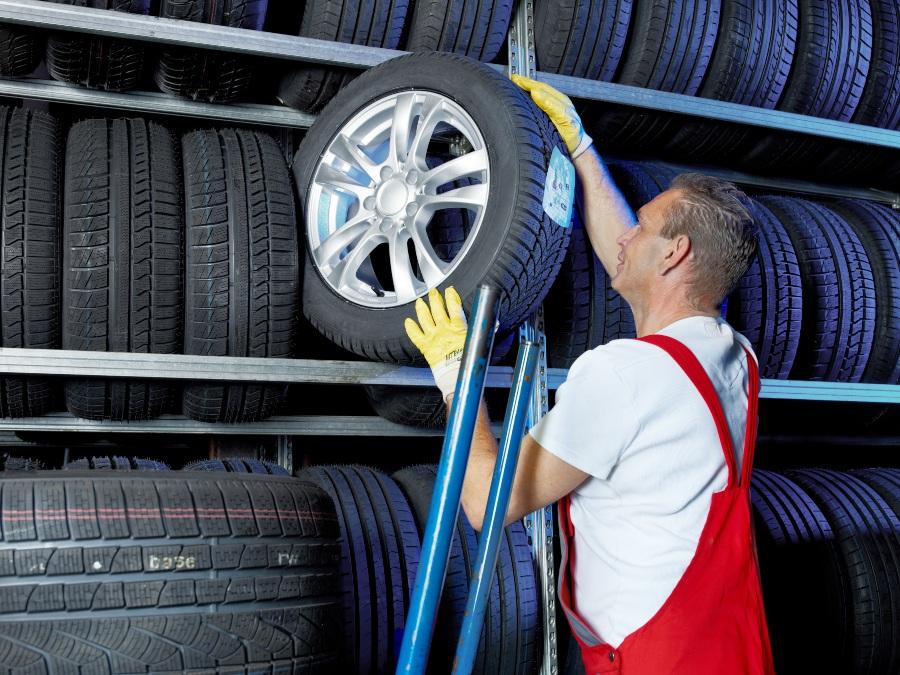 Mechaniker holt Autoreifen aus dem Regal - EU-Reifenlabel