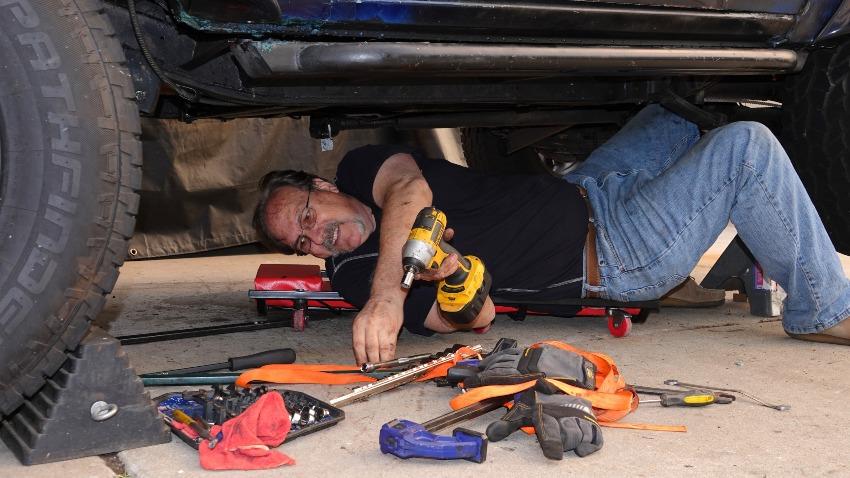 Mann liegt unter einem Auto, um es zu reparieren
