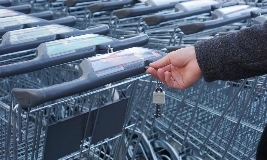 Einkaufswagen-Chip Mann steckt Chip in Einkaufswagen - Einkaufswagenlöser als Werbeartikel