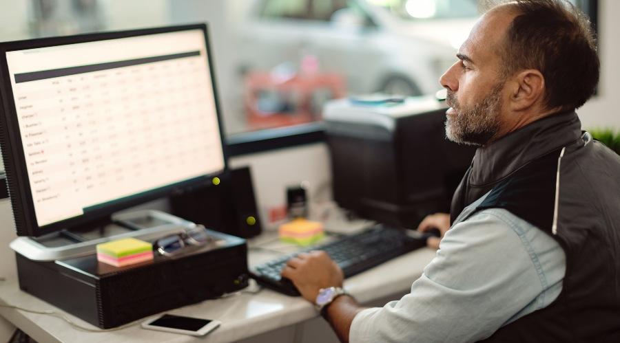 Mechaniker sitzt am Computer - Kfz-Rechnung Muster kostenlos als PDF