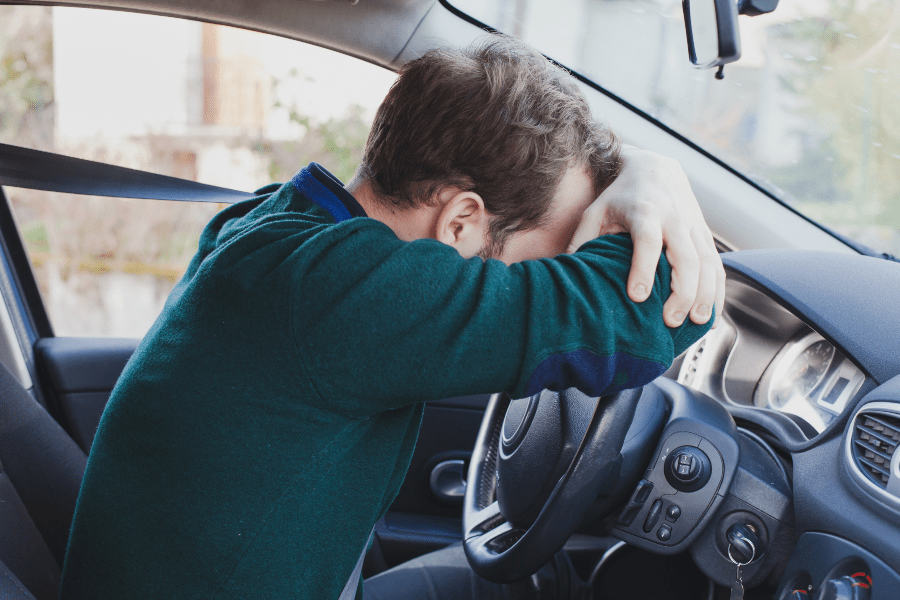 Autofahrer unglücklich über sein Lenkrad gebeugt - falsch getankt