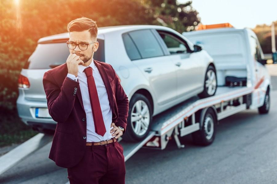 Mann in Anzug muss sein Auto abschleppen lassen