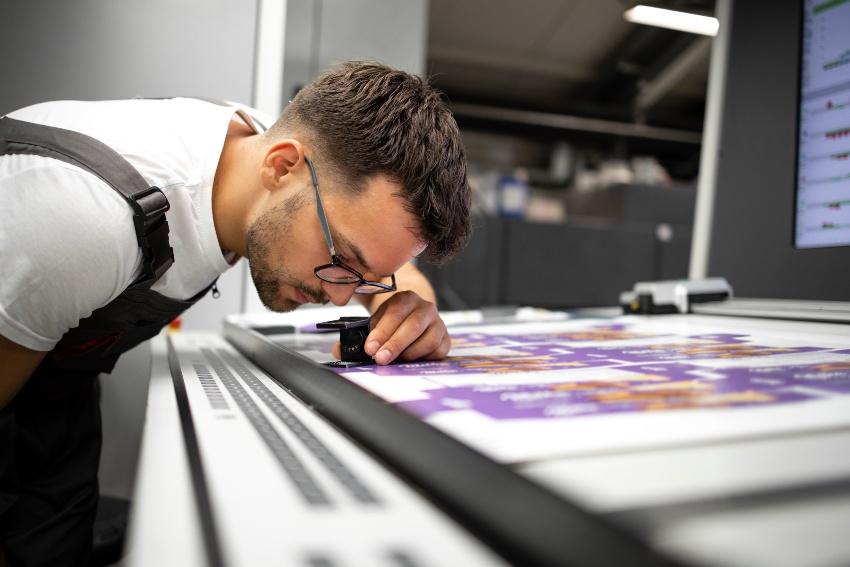 Junger Mann prüft Druckergebnis eines modernen Druckers - Digitaldruck